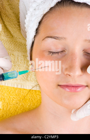 Close up of young woman getting a botox injection in her cheek Stock Photo