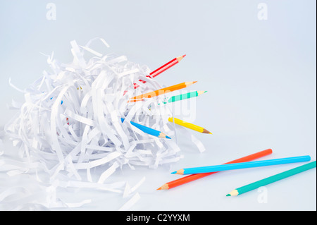 Colored pencils and shredded paper ball over light blue background with soft shadow - concept Stock Photo