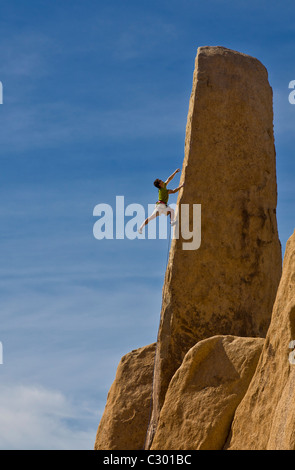 Male rock climber struggles for his next grip on a challenging ascent. Stock Photo