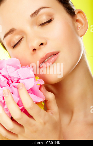Beautiful woman with pink flower over yellow background Stock Photo