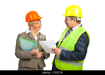 Smiling mature engineers with helmets having conversation and holding folders isolated on white background Stock Photo