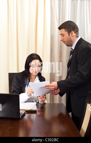 Business man giving a contract for signing to a business woman sitting on chair at table Stock Photo
