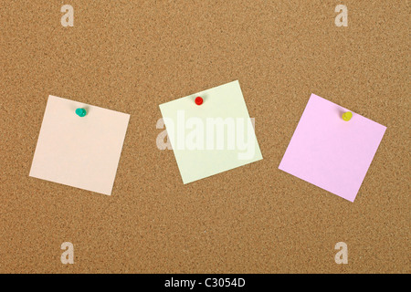 Three note papers attached to cork board with pins. Stock Photo