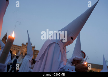 Hooded penitents (Nazarenos) in candlelit procession during Seville's annual Easter Holy Week (Semana Santa de Sevilla) Stock Photo