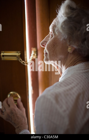 Senior woman using a security chain on front door Stock Photo