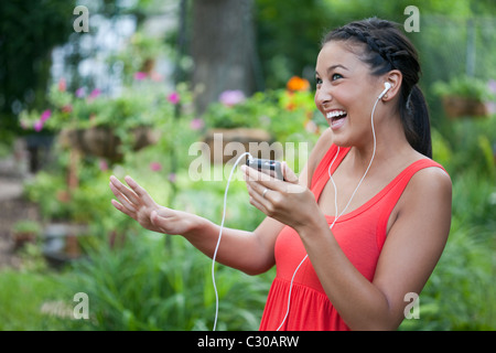 Attractive young Asian woman playfully dances to music on her portable music device. Horizontal shot. Stock Photo