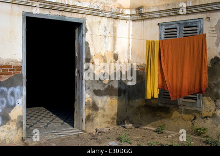 Orange Buddhist monk's robes are hanging on a clothesline at a dilapidated temple in Cambodia. Stock Photo