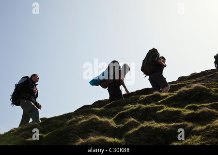 Young people backpacking on Duke of Edinburgh Award scheme expedition climbing up Cat Bells in Lake District National Park Cumbria England UK Britain Stock Photo