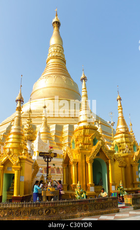 Women pouring water over Buddha statue as part of a Buddhist ritual at the Shwedagon Pagoda in Yangon, Myanmar Stock Photo