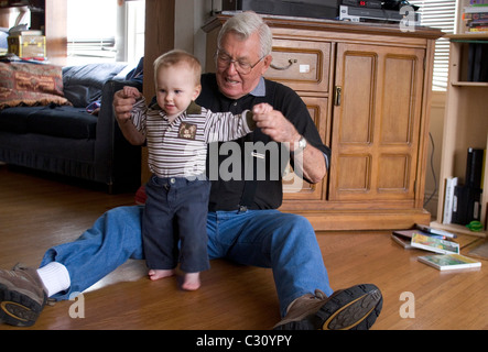 15 month old baby boy taking his first steps as his grandfather watches. Stock Photo