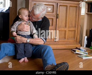 15 month old baby boy taking his first steps as his grandfather watches. Stock Photo