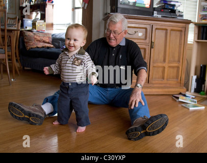 15 month old baby boy taking his first steps as his grandfather watches. Stock Photo