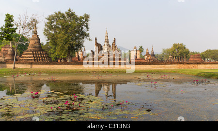 Large Seated Buddha and Temple Ruins of Wat Mahathat With Reflection in Lilly Pond at Sukothai Historical Park in Thailand Stock Photo