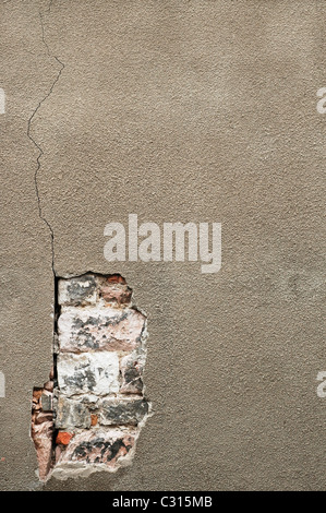 A concrete wall has cracked and crumbled to reveal the old bricks below. Berwick upon Tweed, Northumberland, England, UK Stock Photo