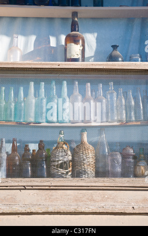 Pink and blue glass bottles line the window sill at the old Ancho train station, Ancho, New Mexico. Stock Photo