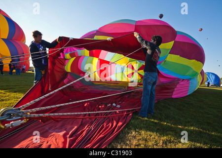 Two men holding the balloon open as it fills up with air. Albuquerque, New Mexico, USA.
