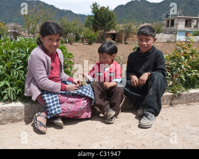 Three young Guatemalan children play on the side of a rural road near their home in Totonicapan, Guatemala. Stock Photo