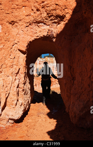 Female hiker enters tunnel on Queens Garden trail, Bryce Canyon national park, Utah, USA Stock Photo