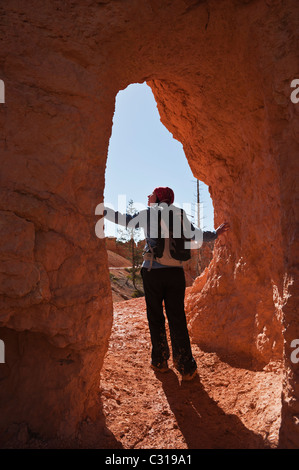 Female hiking looking out from tunnel on Queens Garden trail, Bryce Canyon national park, Utah, USA Stock Photo