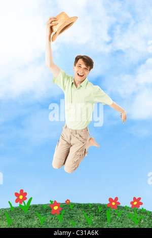 Portrait of joyful man jumping over green grass with blue sky on background Stock Photo
