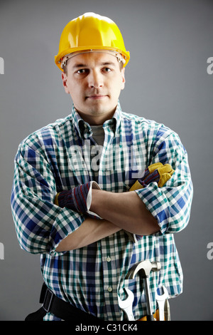 Portrait of confident worker in helmet isolated on grey Stock Photo