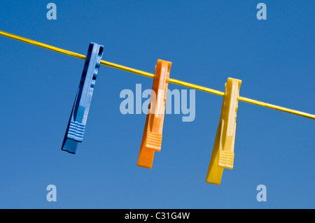 Colourful plastic clothes pegs hanging on a washing line Stock Photo