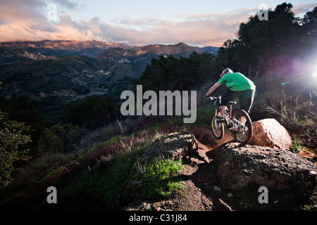 A young man rides his downhill mountain bike on Knapps Castle Trail, surrounded by beautiful scenery in Santa Barbara, CA.