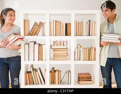 Couple with books standing near bookshelf Stock Photo