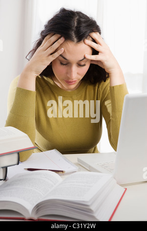 Mixed race woman with headache studying textbooks Stock Photo