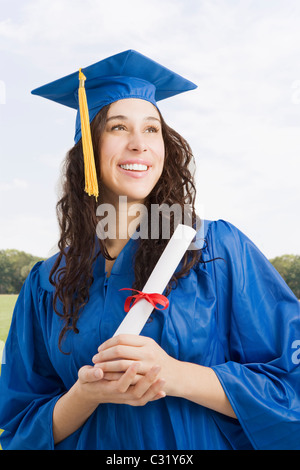 Mixed race woman wearing graduation cap and gown holding diploma Stock Photo