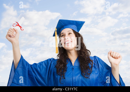 Mixed race woman wearing graduation cap and gown holding diploma Stock Photo