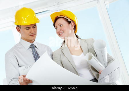 Portrait of two architects in helmets holding blueprint Stock Photo
