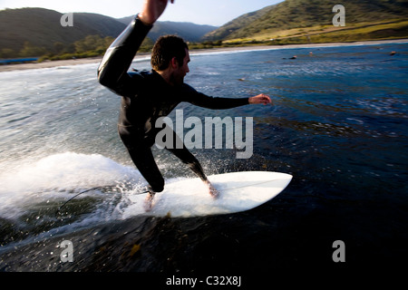 A male surfer does a turn while riding a wave at Leo Carrillo State Park in Malibu, California. Stock Photo