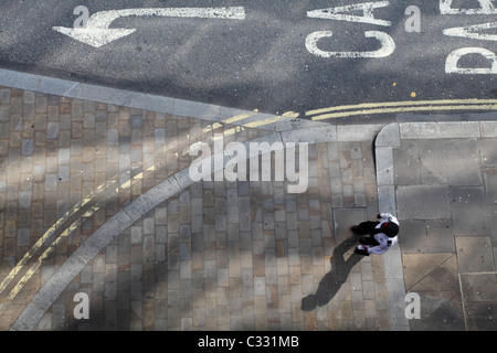 Lone person walking on the pavement with long shadow Stock Photo
