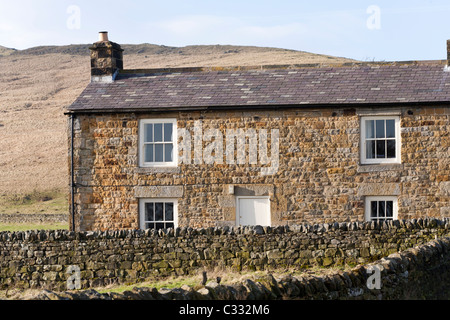 A stone cottage at Once Brewed, Northumberland, England UK - Hadrians Wall runs along the hillside in the background Stock Photo