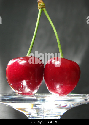 two cherries in light over grey background Stock Photo