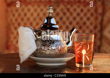 Glass of mint tea and ornate silver teapot served in Morocco, North Africa Stock Photo