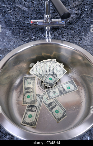 US dollars in a sink drain with water running concept good money going down the drain. Stock Photo