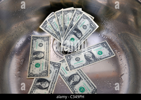 US dollars in a sink drain. Money going down the drain concept. Stock Photo