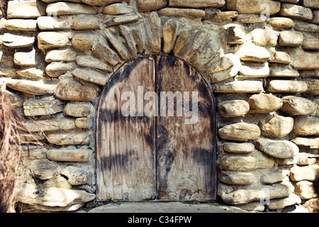 The old arched window in the stone wall with wooden shutters in the medieval style Stock Photo