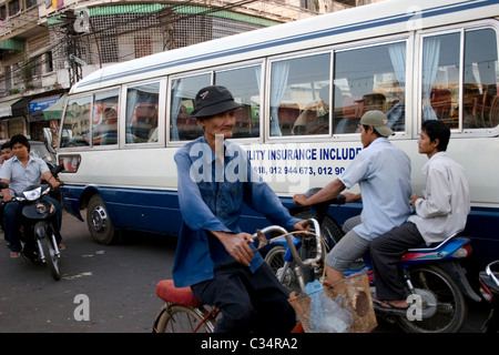 Foreign tourists are riding in a tour bus on a street crowded with heavy traffic in Phnom Penh, Cambodia. Stock Photo