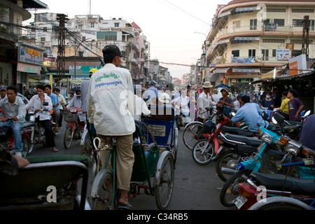 Several cyclo and motorcycle drivers are working on a busy street near a market in Phnom Penh, Cambodia. Stock Photo