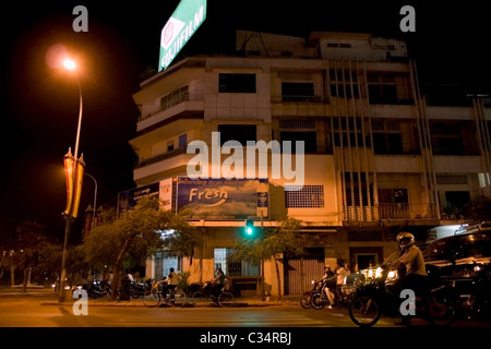 People driving motorcycles and cars are waiting at a traffic light on a busy street in Phnom Penh, Cambodia. Stock Photo