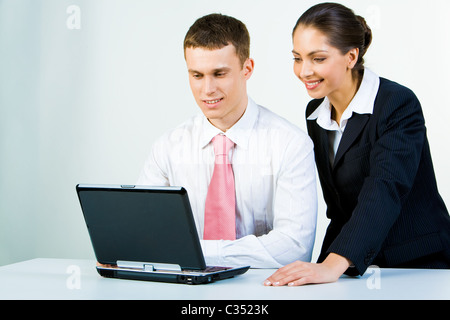 Portrait of two colleagues looking at laptop monitor that is on the table Stock Photo
