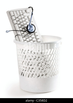 Image of computer keyboard with headphones in the trash bin Stock Photo