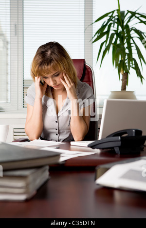 Image of thoughtful businesswoman touching her head while looking at document and reading it Stock Photo