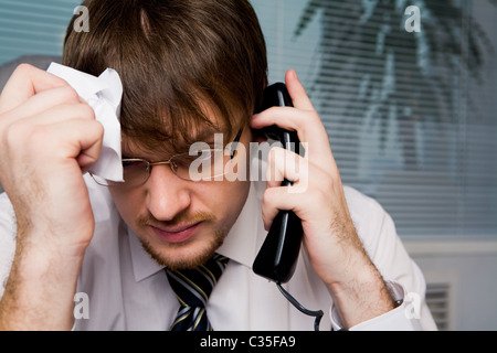 Portrait of frustrated employer calling on the phone and holding crumpled paper in hand Stock Photo