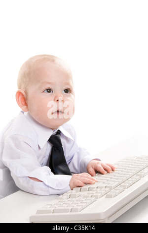 Portrait of serious baby boy typing on keyboard and looking aside Stock Photo