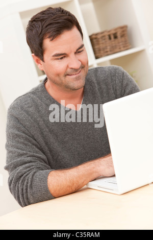 Smiling man in his thirties at home using his laptop computer Stock Photo