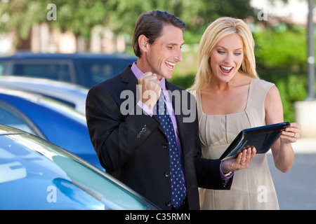 Happy man and woman, businessman and businesswoman team using tablet computer celebrating success Stock Photo